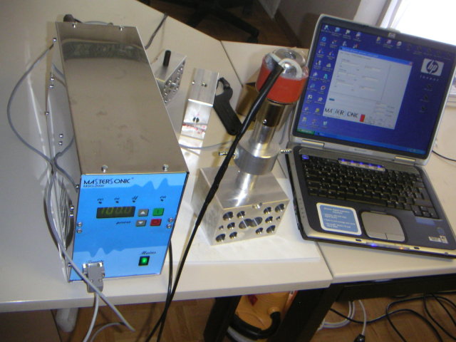 Complete system for ultrasonically-assisted plastic extrusion including computer-controlled generator.
